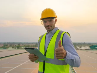 man gives thumbs up while standing on PV rooftop on factory