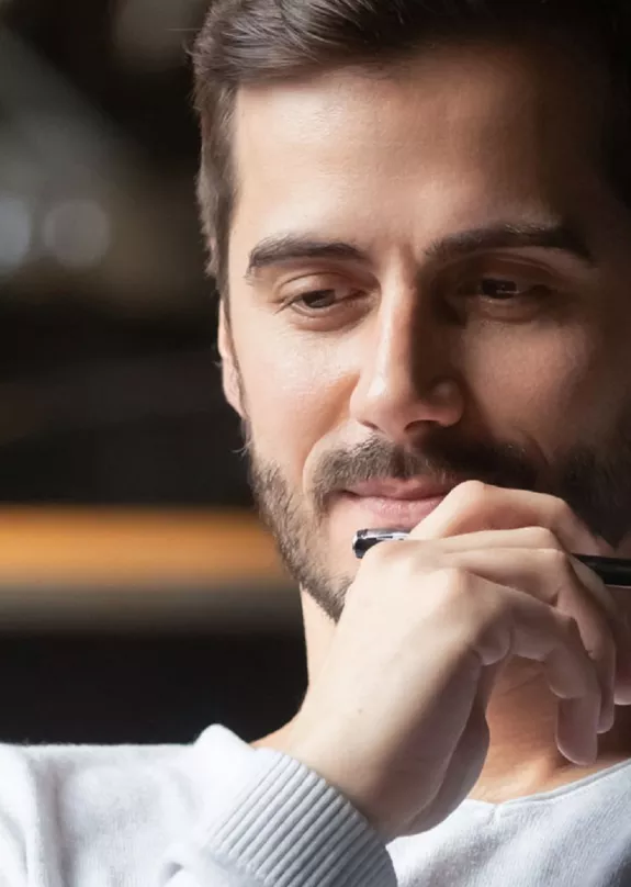 A man holding a pen whilst using a laptop