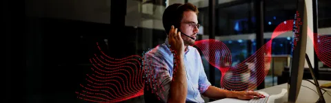 Man speaking on a headset whilst looking at a computer